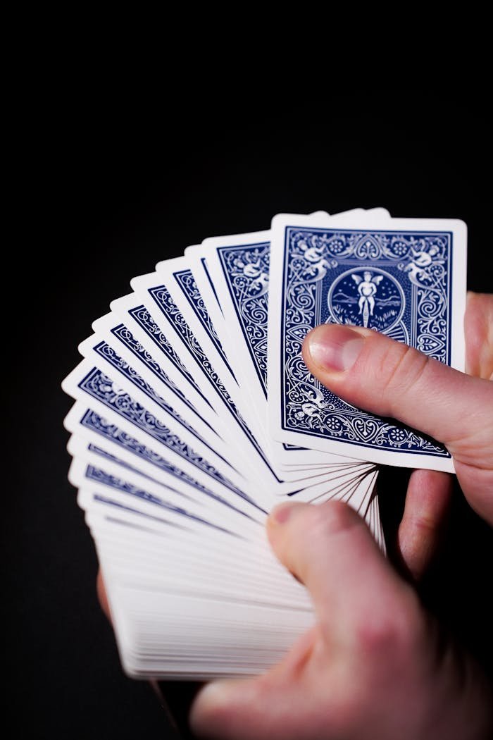 Fanned deck of playing cards in adult hands against a dark background, showcasing skill.
